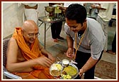 Pujya Tyagvallabh Swami serves puranpuri, sanctified by Swamishri, to the kishores