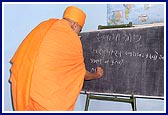 Swamishri writes on the classroom blackboard