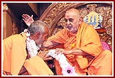 Swamishri offers a garland to Pujya Mahant Swami and blesses him 