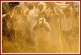 Swamishri begins the traditional spraying of water on devotee as they file pass 