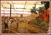 Swamishri begins the traditional spraying of water on devotee as they file pass 