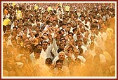 The crowd joyously moves forward to be drenched with the colored, holy water by Swamishri