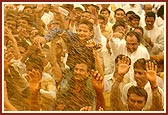 Devotees and sadhus euphorically raise their hands as they are blessed with fragrant holy water