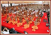 Swamishri and the parshads and sadhaks raise the new janois during the initiation ceremony