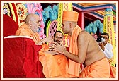 Swamishri blesses and gives the guru mantra to the newly initiated sadhus and parshads