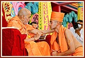 Swamishri blesses and gives the guru mantra to the newly initiated sadhus and parshads