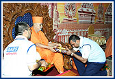 Swamishri blesses and presents a gift to a devotee for his performance as a topper in Satsang Exams