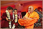 Swamishri garlands two young schoolchildren