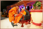 Ghanshyamcharan Swami welcomes Swamishri with an orange rose garland