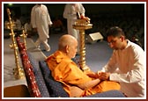 A kishore tying a nada chaddi to Swamishri as part of the opening ceremony