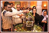 Devotees offering their devotion by performing abhishek of the Shivaling with milk and bilipatras