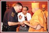 Swamishri teaches Policeman Allen Sabo how to do the mala 