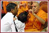 Swamishri performing the Chaul-Sanskar (cutting the hair for the first time)