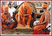 Swamishri places rice grains into the foundation