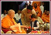 Swamishri gives a flower to a child that narrated a story during his pooja 