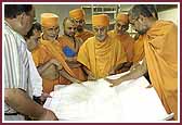 Swamishri studies the architectural plans for BAPS