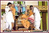 Swamishri is greeted by Sant Shri Rameshbhai Oza and Shri Bhagwatbhai