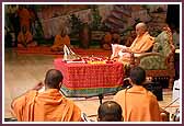 Swamishri performs mala during his morning puja as saints sing kirtans