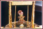 Lord Harikrishna Maharaj graces a decorative swing during Swamishri's morning pooja