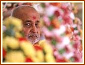 Swamishri seated on a swing decorated with flowers