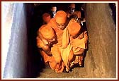 Swamishri being carried on a flight of stairs to a Buddhist cave