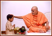 At 10.30 pm, before retiring to bed Swamishri patiently blesses a child, listens to him and pleases him with a handful of chocolates. Even after a hectic day of activities Swamishri responds with joy, freshness and humor at the child's casual and innocent talk.