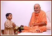 At 10.30 pm, before retiring to bed Swamishri patiently blesses a child, listens to him and pleases him with a handful of chocolates. Even after a hectic day of activities Swamishri responds with joy, freshness and humor at the child's casual and innocent talk.