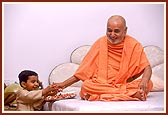 At 10.30 pm, before retiring to bed Swamishri patiently blesses a child, listens to him and pleases him with a handful of chocolates. Even after a hectic day of activities Swamishri responds with joy, freshness and humor at the child's casual and innocent talk.