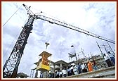 Being elevated to the mandir floor in a cabin by the construction crane