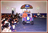 Thakorji and Swamishri are welcomed with a shower of flower petals in the Shibir