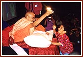 Swamishri entertains boy trying to grab a packet of prasad