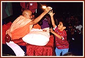 Swamishri entertains boy trying to grab a packet of prasad