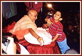 Swamishri entertains boy trying to grab a packet of prasad