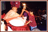 Swamishri entertains boy trying to grab a packet of prasad