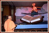 Swamishri gently swinging the murti of Lord Swaminarayan seated in a swan hindolo