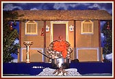 Swamishri blesses the assembly with Sura Khachar's darbar as a backdrop and a large steel pot on a log fire in the foreground