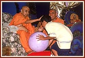 Placing his hand on the balak's shoulder, Swamishri listens to his enquiry with interest