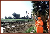 Swamishri sanctifies the proposed new mandir site by sprinkling flowers