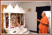 Swamishri performs pujan and arti of Thakorji installed in a ghar mandir at a devotee's house 