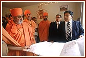 Swamishri views the plans for the new mandir