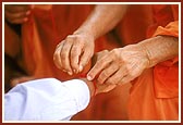 Nadachhadi: Swamishri ties nadachhadi on a devotee's wrist