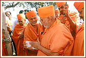 Swamishri observes and feels a red-stone brick for the Shilanyas ceremony