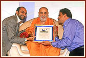 Yogesh Patel (r) and Tarun Patel with Swamishri holding the Guinness World Record Certificate for the world's largest Annakut at the Shri Swaminarayan Mandir in London