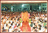 Swamishri is welcomed with a shower of flowers and deafening applause by the devotees in the new Satsang hall