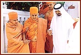 The Sheikh holds Swamishri's hand and sees him to the palace gate