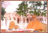 Swamishri performs his morning puja with the Shri Swaminarayan Mandir, Sankari in the backdrop