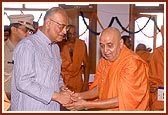 Swamishri welcomes and offers a gift to the Governor Shri Dineshnandan Sahay