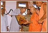 Swamishri welcomes and offers a gift to the Governor Shri Dineshnandan Sahay