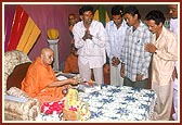 Swamishri sanctifies the bricks with rice grains, flowers, gulal and holy water for the school in Paandri village