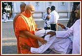 Swamishri patiently enquires the wellbeing of an aged devotee and blesses him&nbsp;
